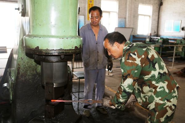 李根生和工友配合在空气锤前赶工自制件 李根生和工友配合在空气锤前赶工自制件